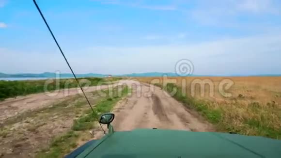 一辆绿色的大吉普车沿着泥泞的乡村道路行驶景色优美视频的预览图