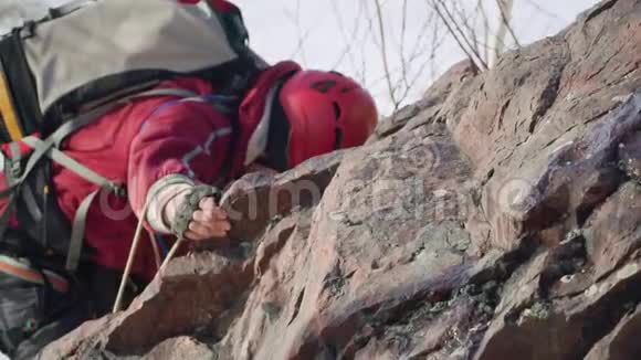 攀爬者紧紧抓住他的手越过岩石的边缘站在上面他带着沉重的背包装备视频的预览图