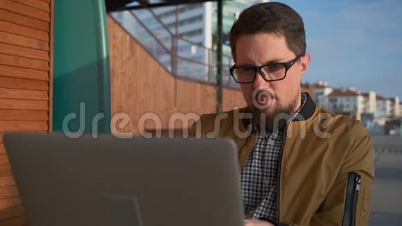 放松的男人正在城市街道上观看笔记本电脑脸上的特写视频的预览图