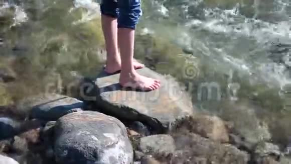 山河那家伙站在岩石上水绕着他的脚和石头流清晨的旅行者视频的预览图