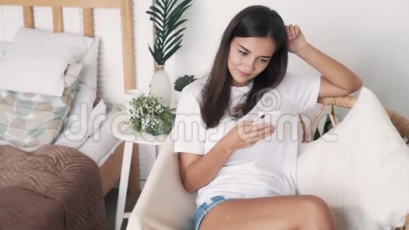 漂亮的女孩坐在草椅上用电话上网购物动作缓慢视频的预览图