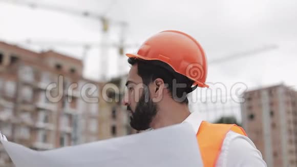 微笑的建筑工人戴着橙色头盔看镜头的肖像建筑工程的建设者视频的预览图