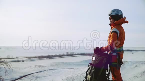 女孩登山者站在山顶在他的背包旁边看着远处的风景视频的预览图