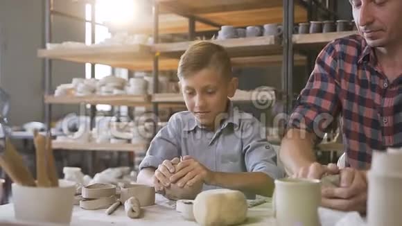 可爱的父亲教小儿子如何在陶工轮上用粘土工作视频的预览图