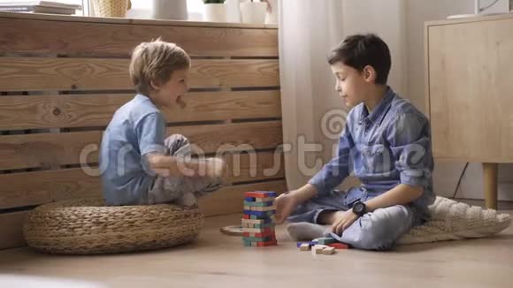两个男孩的兄弟正在用坐在地板上的木块建造一座塔视频的预览图