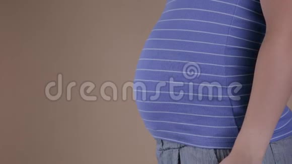 一个穿着睡衣的年轻孕妇的真实特写镜头正在抚摸她早上刚醒来的腹部视频的预览图
