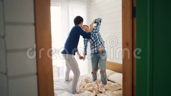 快乐的年轻人在家里的床上跳舞移动身体牵手享受爱情和闲暇时光视频的预览图