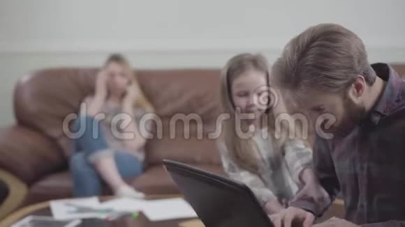 有胡子的人用笔记本电脑近距离工作的肖像小女孩摸着男人的手他给了她钱这就是视频的预览图