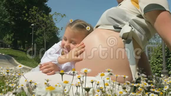 一个小女孩在花丛中拥抱她怀孕的母亲视频的预览图