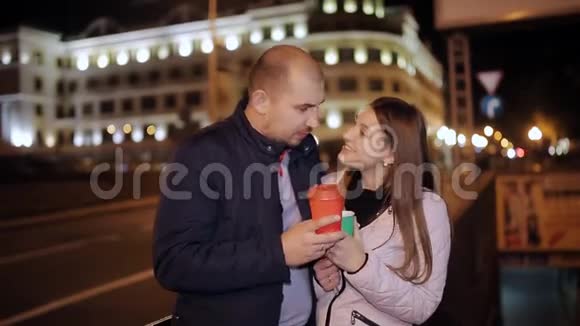 晚上在城里的情侣从大路上喝着咖啡说话笑着接吻视频的预览图