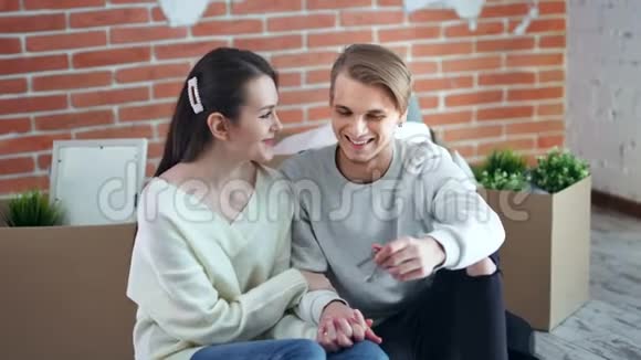 年轻的微笑夫妇享受购买并搬到新的公寓手拿钥匙中拍视频的预览图