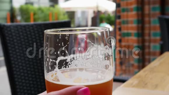 一个女人手拿着一杯啤酒放在桌子上欧洲城市的街头咖啡馆视频的预览图