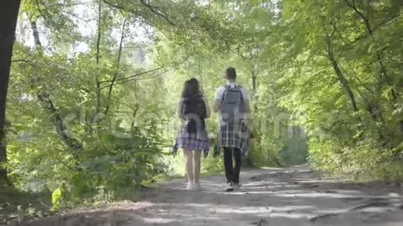 在森林里散步的男孩和年轻可爱女孩的肖像旅行者与户外背包的配对休闲夫妇视频的预览图
