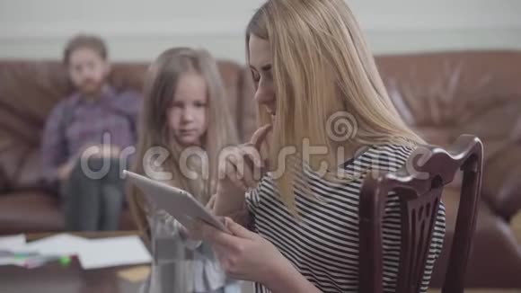 一幅漂亮的金发女人用平板电脑特写的肖像小女孩试图引起人们的注意视频的预览图