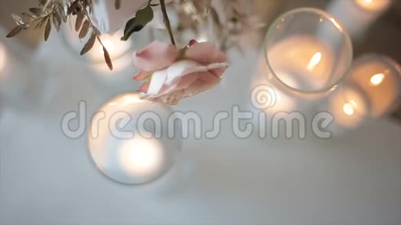 玫瑰花装饰在模糊的背景上从灯光的眩光从燃烧的蜡烛优雅的晚间装饰视频的预览图