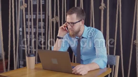 男企业主坐在办公室里兴高采烈地用手机说话视频的预览图