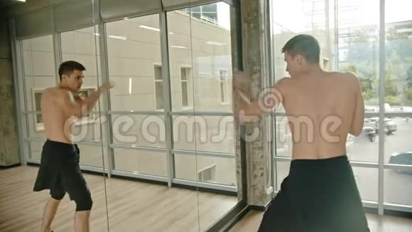 一个运动员在摄影棚里对着镜子练拳击视频的预览图
