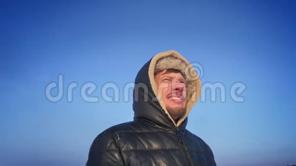 绕着兜帽里的中年探险家的视野微笑地看着雪漠上的太阳视频的预览图
