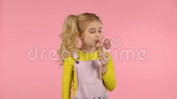 粉红背景画室里有棒棒糖的漂亮女孩视频的预览图