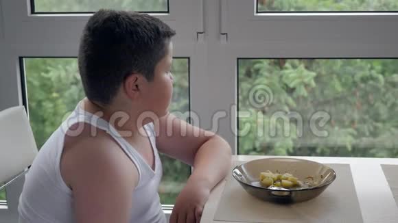 小胖小子坐在窗边吃着好吃的儿童肥胖视频的预览图
