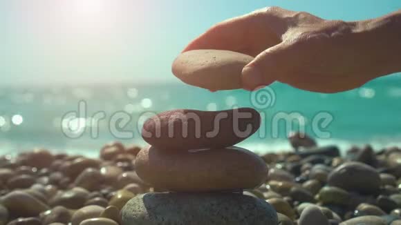 在卵石滩上用手建造石头金字塔稳定禅和谐平衡的概念视频的预览图