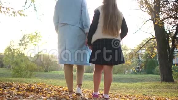 母女俩在城市公园散步后景一个穿蓝色斗篷的女人和一个十几岁的女孩走进来视频的预览图