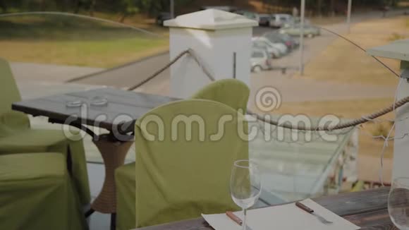 一个漂亮的女人坐在开放式露台上的一家餐馆的桌子旁把电话放在桌子上视频的预览图