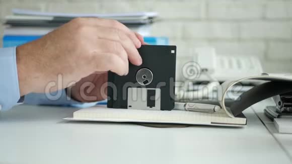 办公室里的人手里拿着一张软盘坐在桌子上视频的预览图