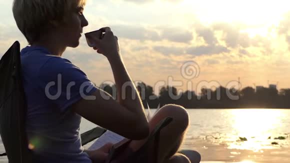 明亮的人在SloMo日落时用折叠椅和记事本喝咖啡视频的预览图