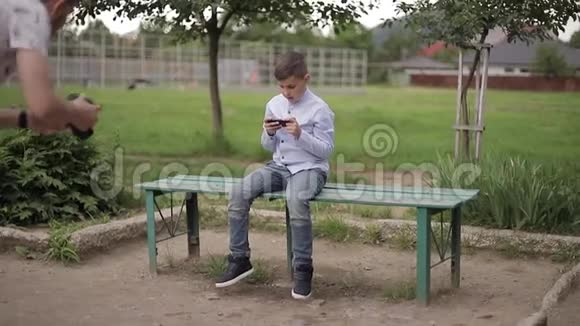 放学后坐在长凳上玩网络游戏的帅哥视频的预览图