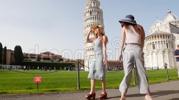 意大利比萨两个穿着睡衣的年轻女人在光明的一天走在比萨斜塔的背景上视频的预览图