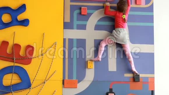 小女孩爬上室内的攀爬墙婴儿在操场上玩孩子们体育游戏视频的预览图
