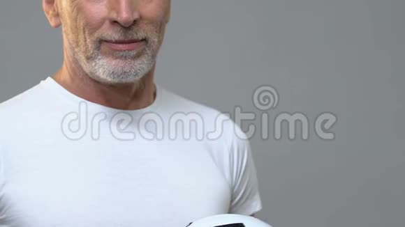 老年健康男子在灰色背景下踢球球队教练视频的预览图