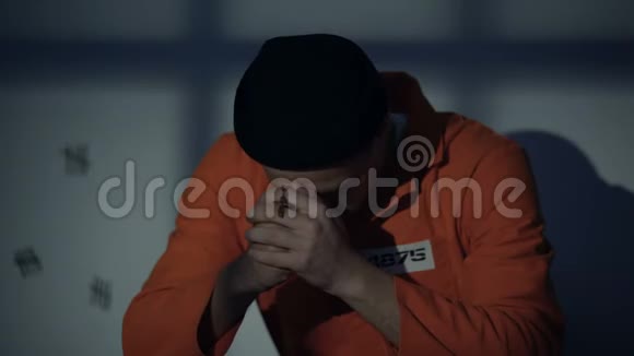 欧洲被监禁的男性手持银十字架在牢房里祈祷感到内疚视频的预览图