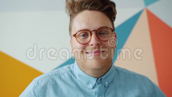 流行眼镜中快乐的男人在彩色背景上微笑的肖像视频的预览图