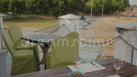 一个漂亮的女人坐在开放式露台上的一家餐馆的桌子旁把电话放在桌子上视频的预览图