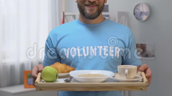开朗的志愿者端着营养早餐的托盘帮助老人和穷人视频的预览图