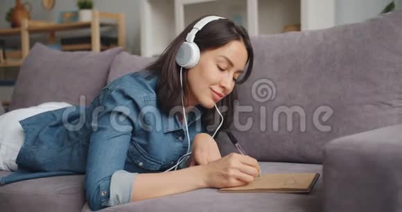 戴着耳机听音乐在笔记本上画图画的美女视频的预览图