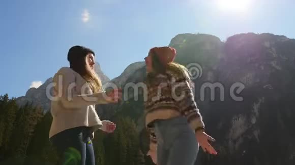 年轻人旅行两个年轻的女人站在一座山的背景上玩得很开心视频的预览图