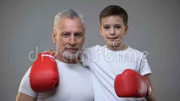 积极的老年男性和男孩戴着拳击手套寻找相机健康的生活方式视频的预览图