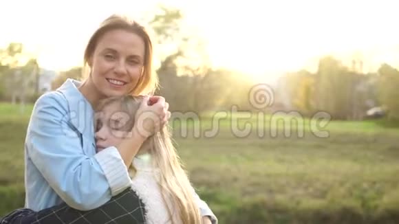 日落时分快乐的母亲和她十几岁的女儿拥抱在秋天公园散步母亲和女儿母亲日视频的预览图