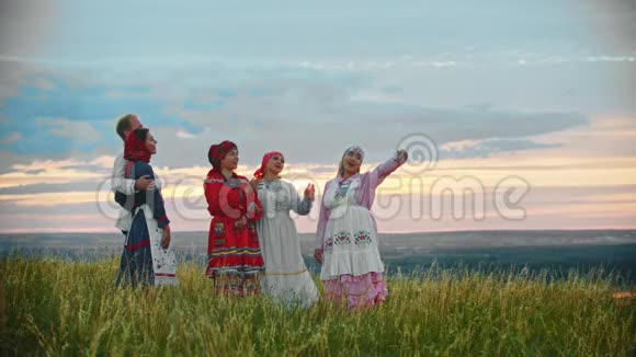 人们穿着传统的俄罗斯民族服装站在田野上自拍视频的预览图