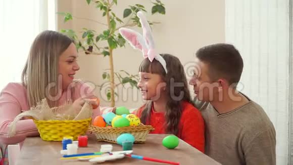 爸爸妈妈看着女儿然后在镜头里出示复活节彩蛋我女儿戴着兔子耳朵视频的预览图