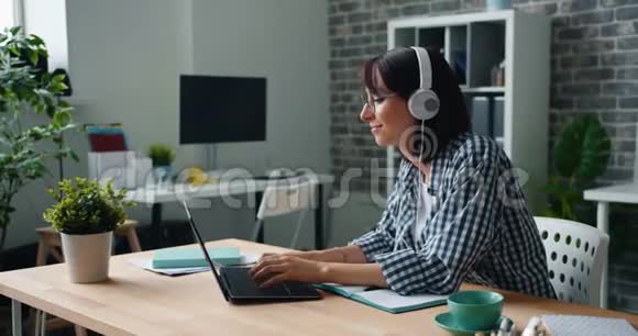 女潮头在工作中享受乐趣听音乐跳舞在笔记本电脑上打字视频的预览图