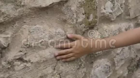 年轻的手触摸户外的旧石墙近距离少年手摸老街上的石墙表面视频的预览图