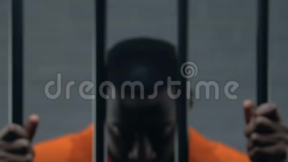 在囚室里关着铁条看着摄像机的非裔美国囚犯犯了罪视频的预览图
