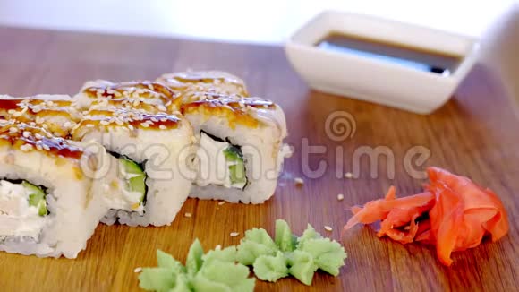 女人吃的面包里有鱼和芝麻上面有芥末生姜和酱油的木板双手并拢视频的预览图