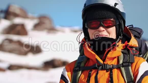 特写镜头登山者戴着头盔和保暖夹克站在山上用手固定眼镜视频的预览图