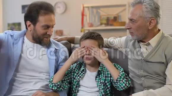 男孩闭着眼睛坐着爸爸和爷爷送生日礼物惊喜视频的预览图