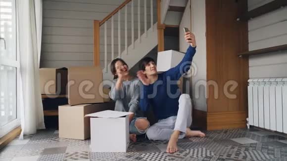 漂亮的年轻女士和她的丈夫正在搬迁期间用智能手机进行在线视频通话人们展示了新的视频的预览图